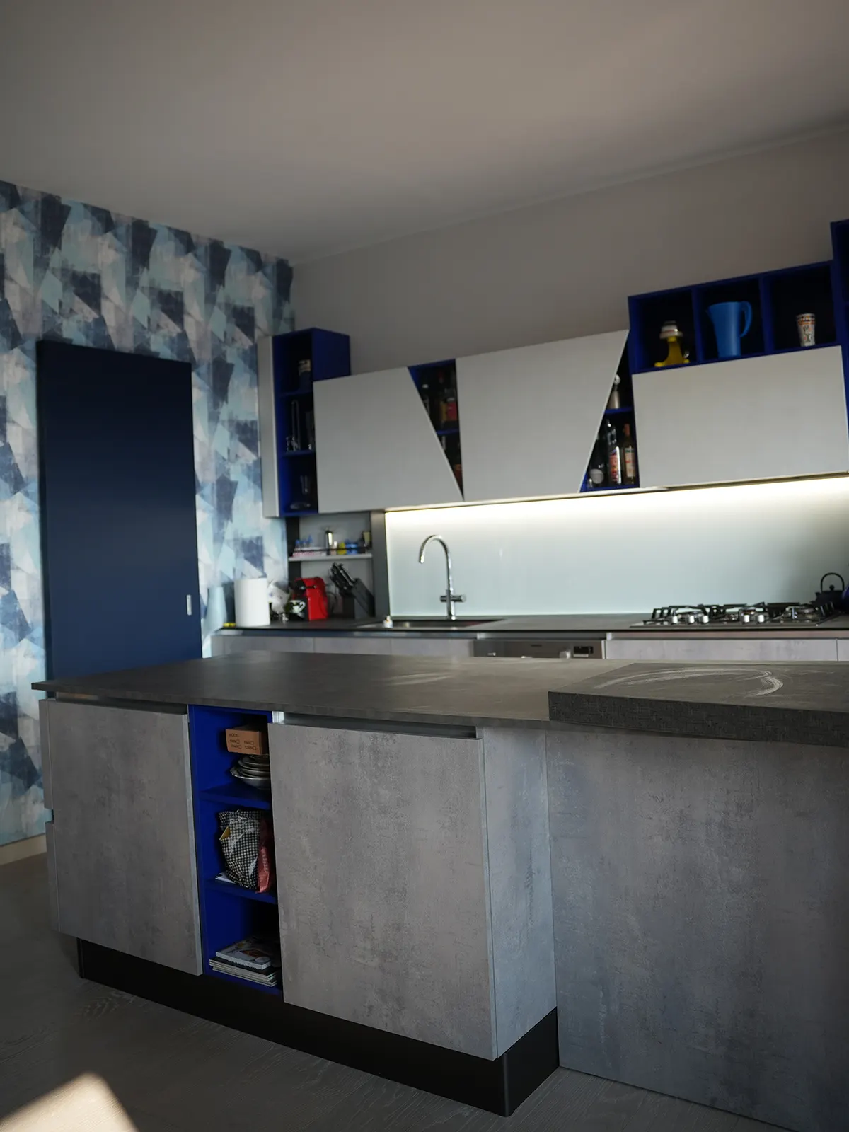 Cucina moderna con carta da parati geometrica e arredi blu in appartamento a Torino