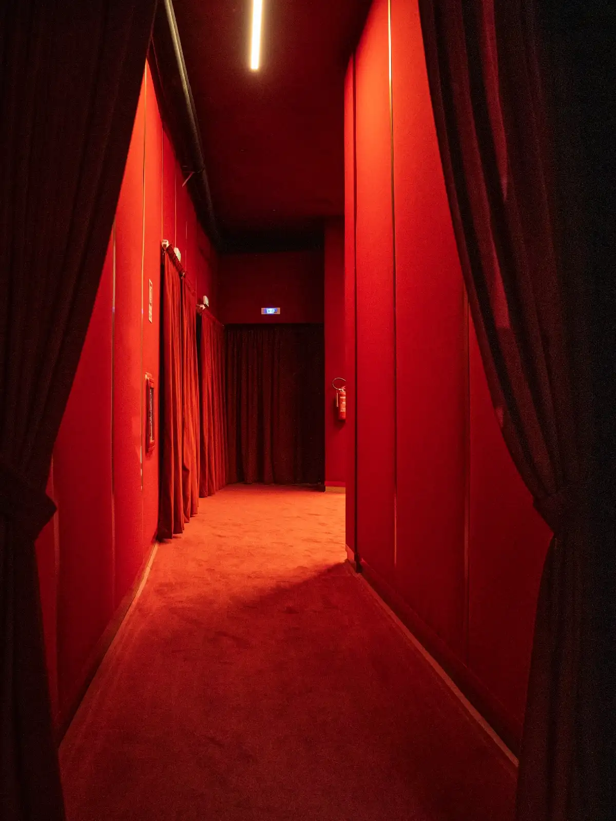 Sala interna del Cinema Eliseo a Torino dopo l&rsquo;intervento di riqualificazione architettonica, vista del corridoio della sala rossa