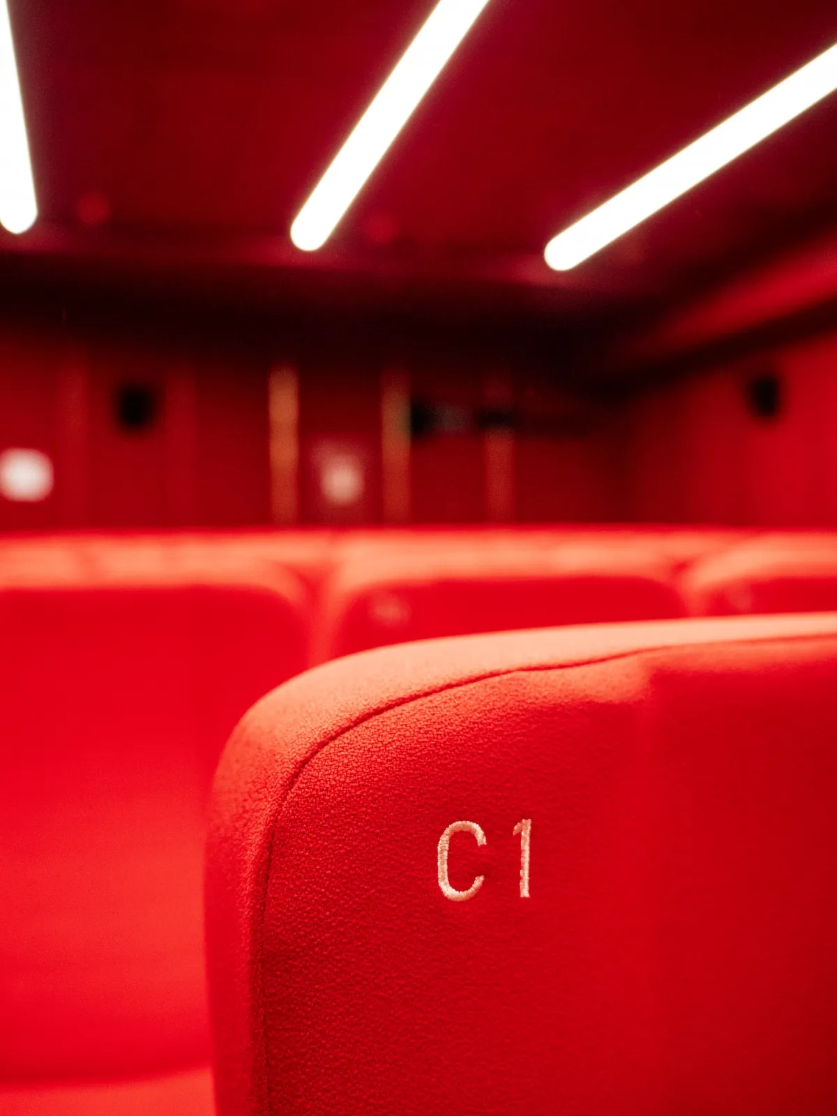 Sala interna del Cinema Eliseo a Torino dopo l&rsquo;intervento di riqualificazione architettonica, dettagli delle sedute e dell'illuminazione della sala rossa