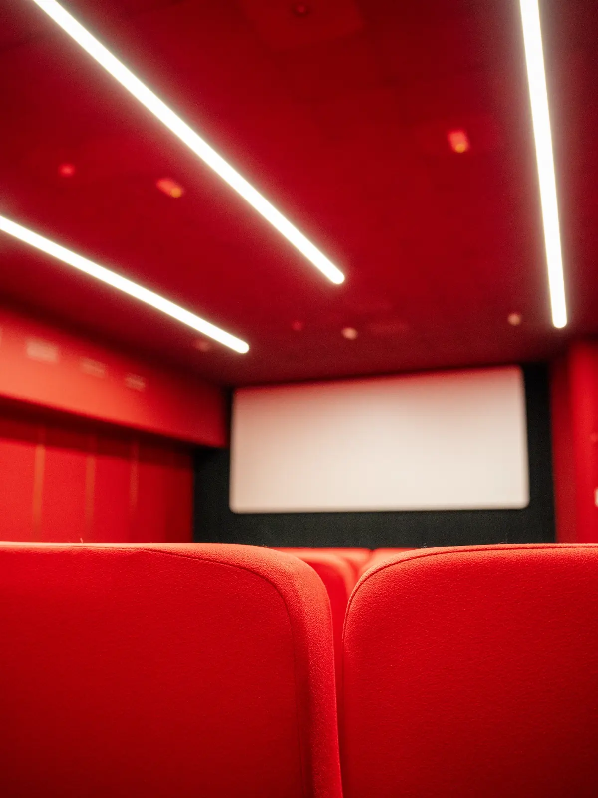 Sala interna del Cinema Eliseo a Torino dopo l&rsquo;intervento di riqualificazione architettonica, dettagli delle sedute, dello schermo e dell'illuminazione della sala rossa