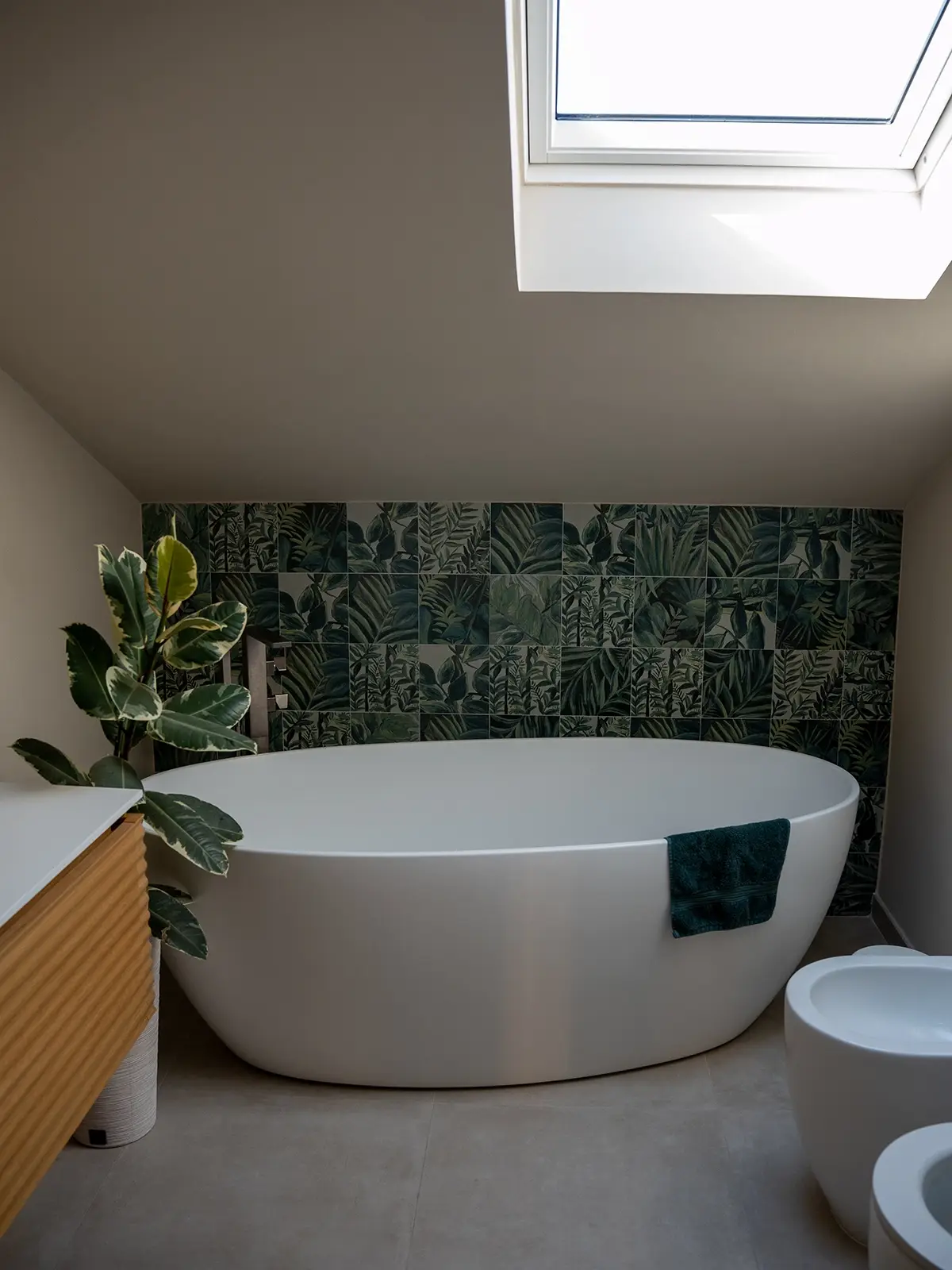 Bagno con vasca freestanding sotto lucernario e rivestimento decorativo verde, progetto di interior design a Torino