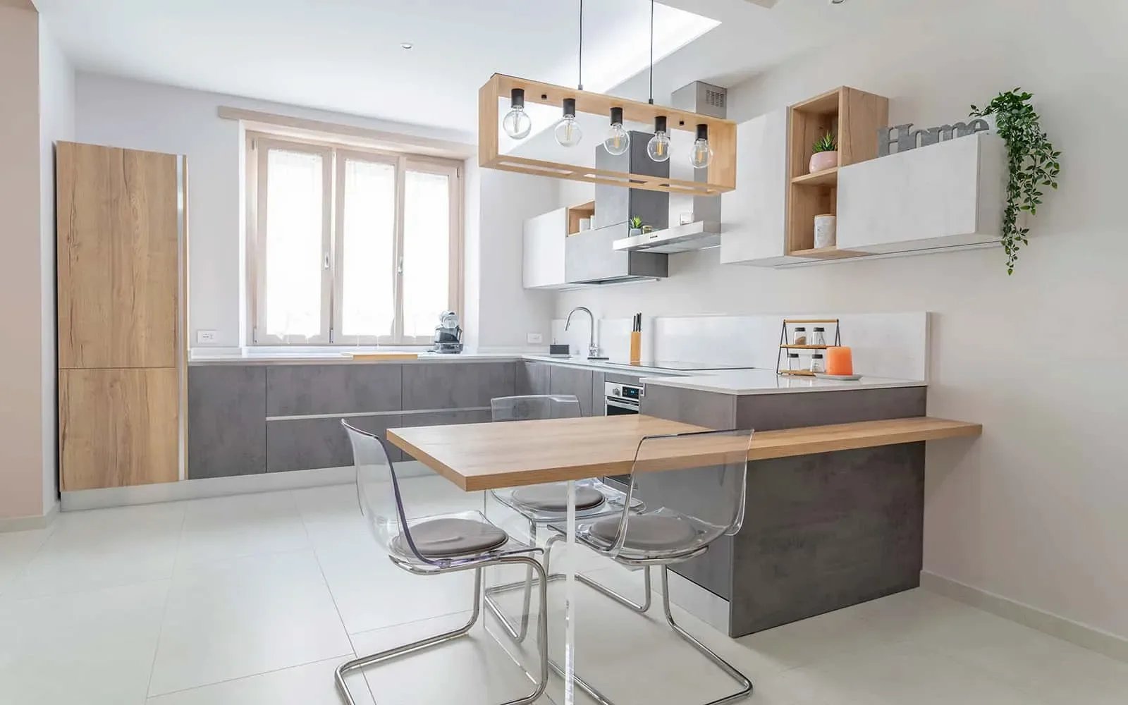 Cucina open space con penisola in legno, sedute trasparenti e finiture contemporanee in appartamento ristrutturato a Torino
