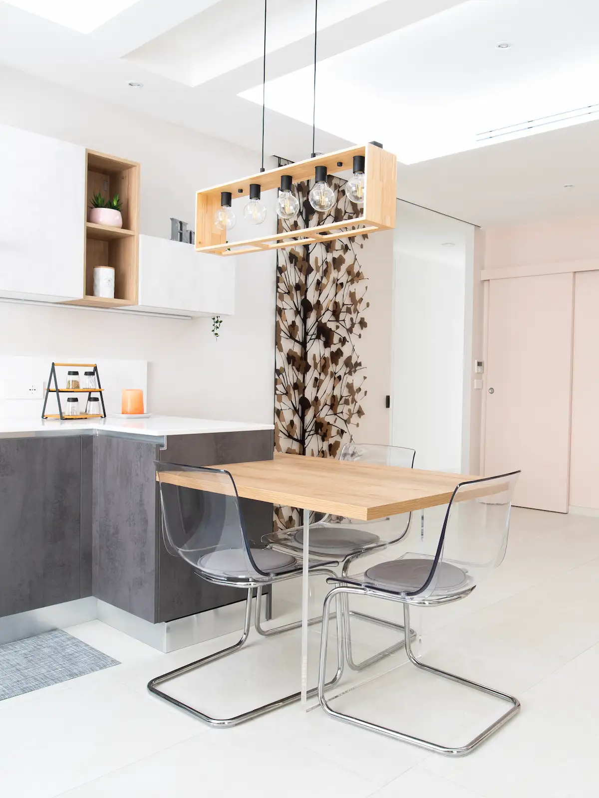 Cucina open space con tavolo in legno e sedute trasparenti in appartamento ristrutturato a Torino