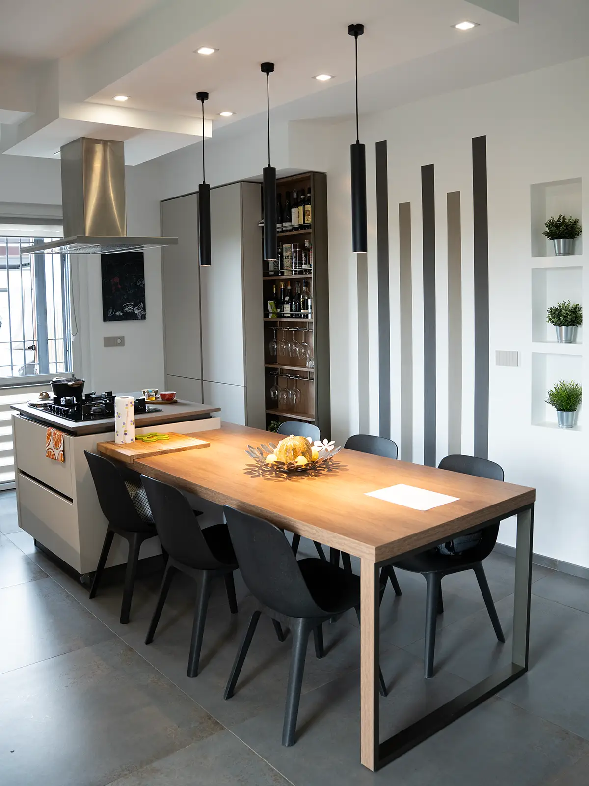 Cucina moderna su misura con isola centrale, illuminazione a sospensione e dettagli materici in una villetta contemporanea a Torino.