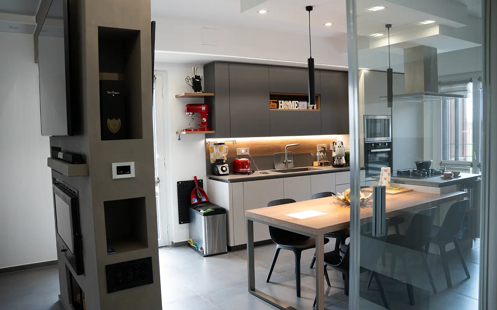 Cucina su misura con arredi minimal, illuminazione LED e vetrata scorrevole interna in una villetta a schiera moderna a Torino.