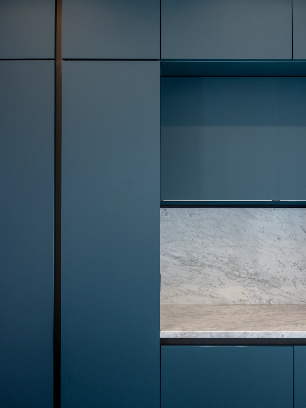 Composizione minimal della cucina in un progetto di interior design a Chieri con colonne scure, rivestimento effetto marmo e geometrie pulite contemporanee.