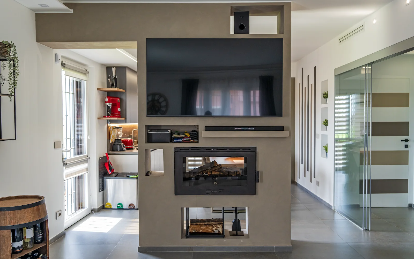 Soggiorno open space in un progetto di interior design a Torino con parete camino e televisione integrata, elemento divisorio tra cucina e zona living contemporanea.