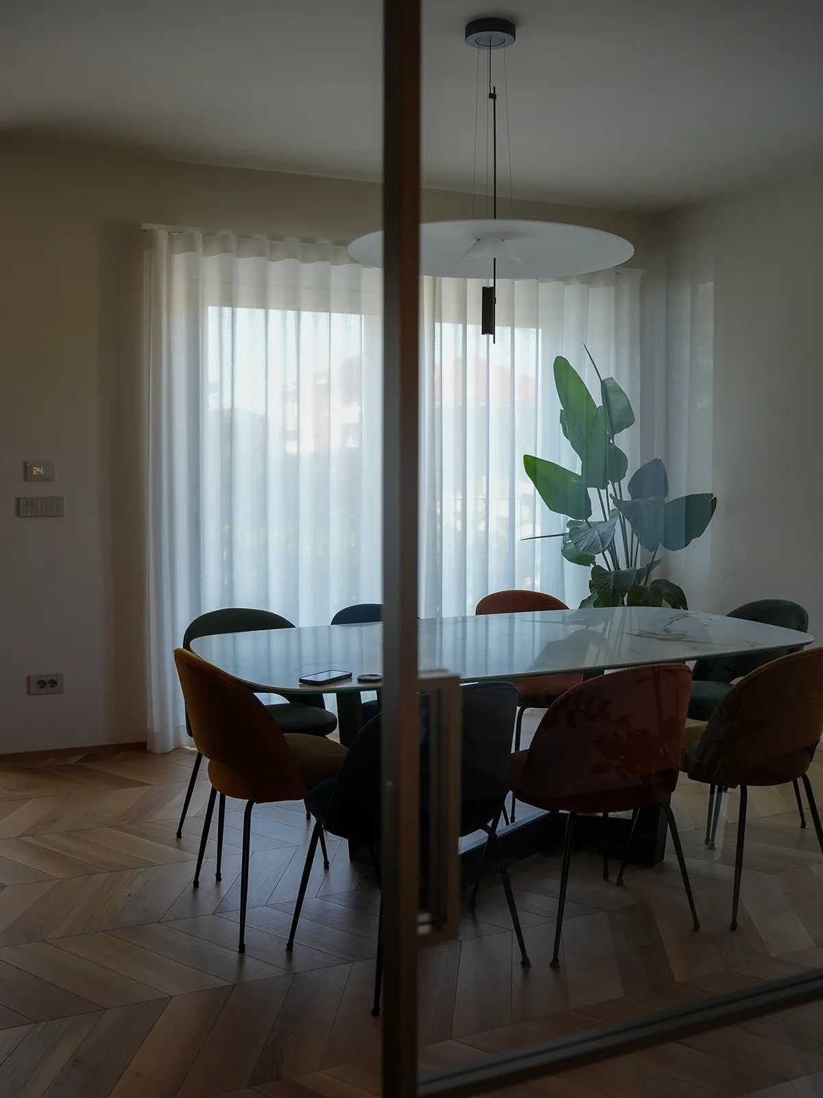 Sala da pranzo con tavolo effetto marmo, sedute colorate e luce naturale filtrata in un appartamento a Torino