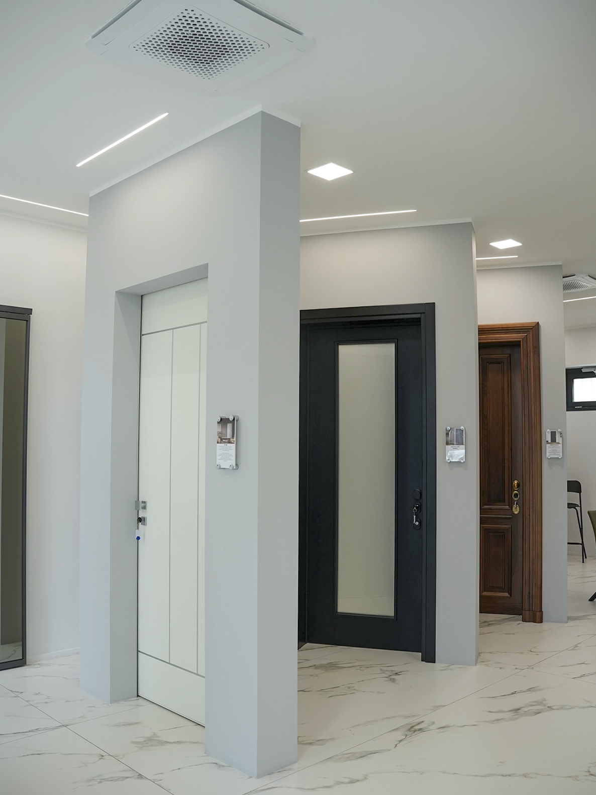 Area espositiva dello showroom Porta Nuova a Torino con porte moderne, pavimento effetto marmo e interior design minimal contemporaneo.