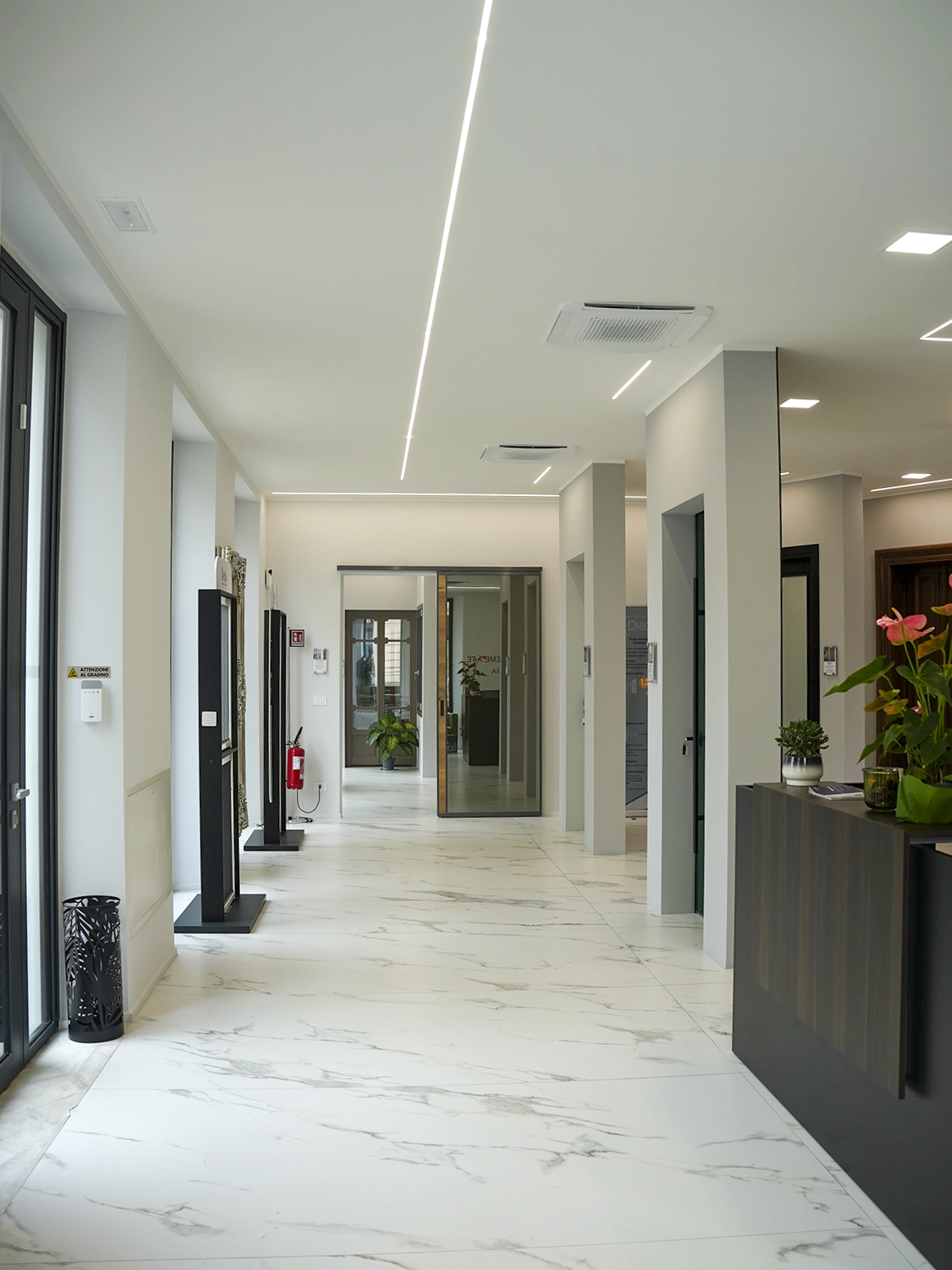 Vista interna dello showroom Porta Nuova a Torino con area espositiva, pavimento effetto marmo e illuminazione lineare dal design minimal contemporaneo.
