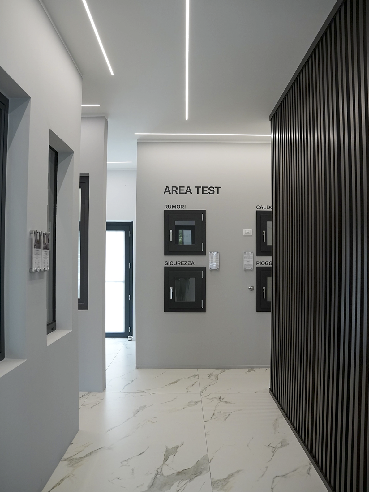 Area test dello showroom Porta Nuova a Torino dedicata a serramenti e infissi con design minimal, illuminazione lineare e pavimento effetto marmo.