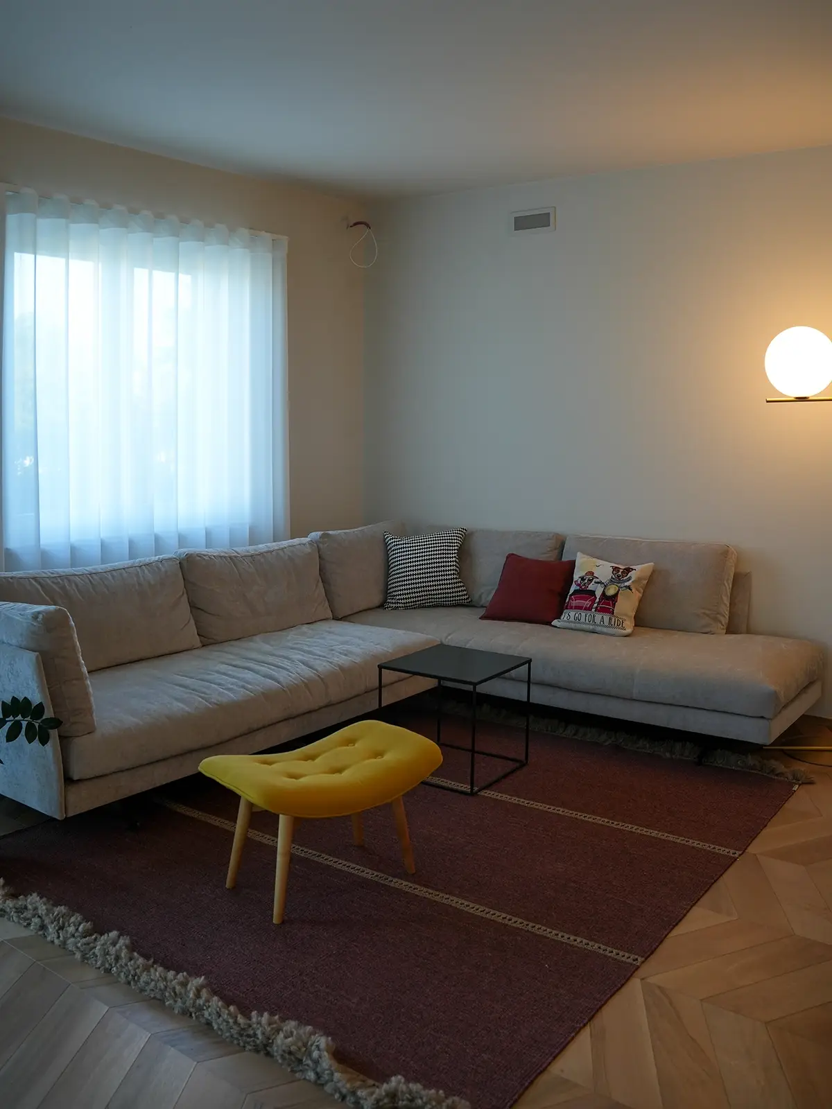 Soggiorno con divano angolare, tappeto e pouf colorato in un appartamento ristrutturato a Torino