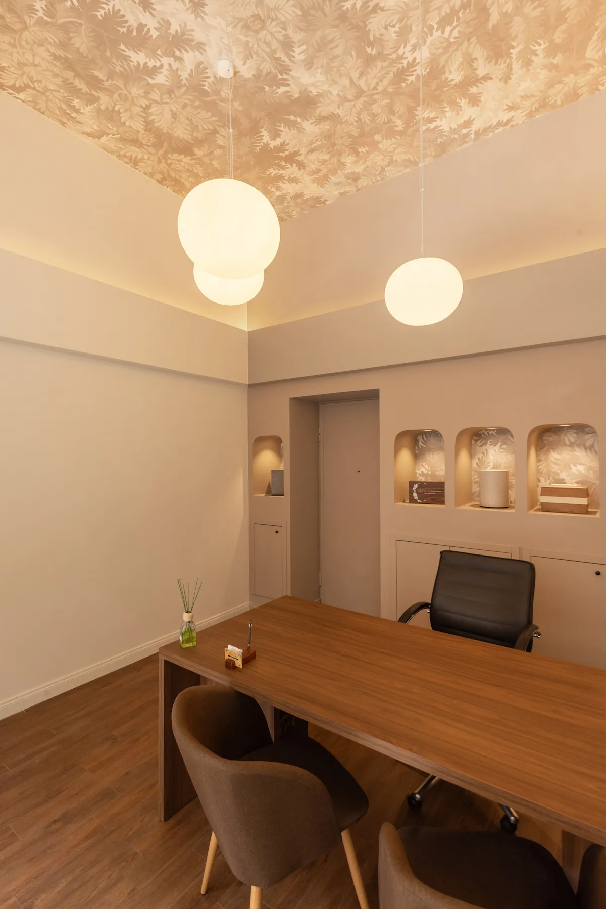 Ufficio di un'agenzia di pompe funebri ristrutturata a Torino con illuminazione scenografica, arredi in legno e nicchie illuminate.