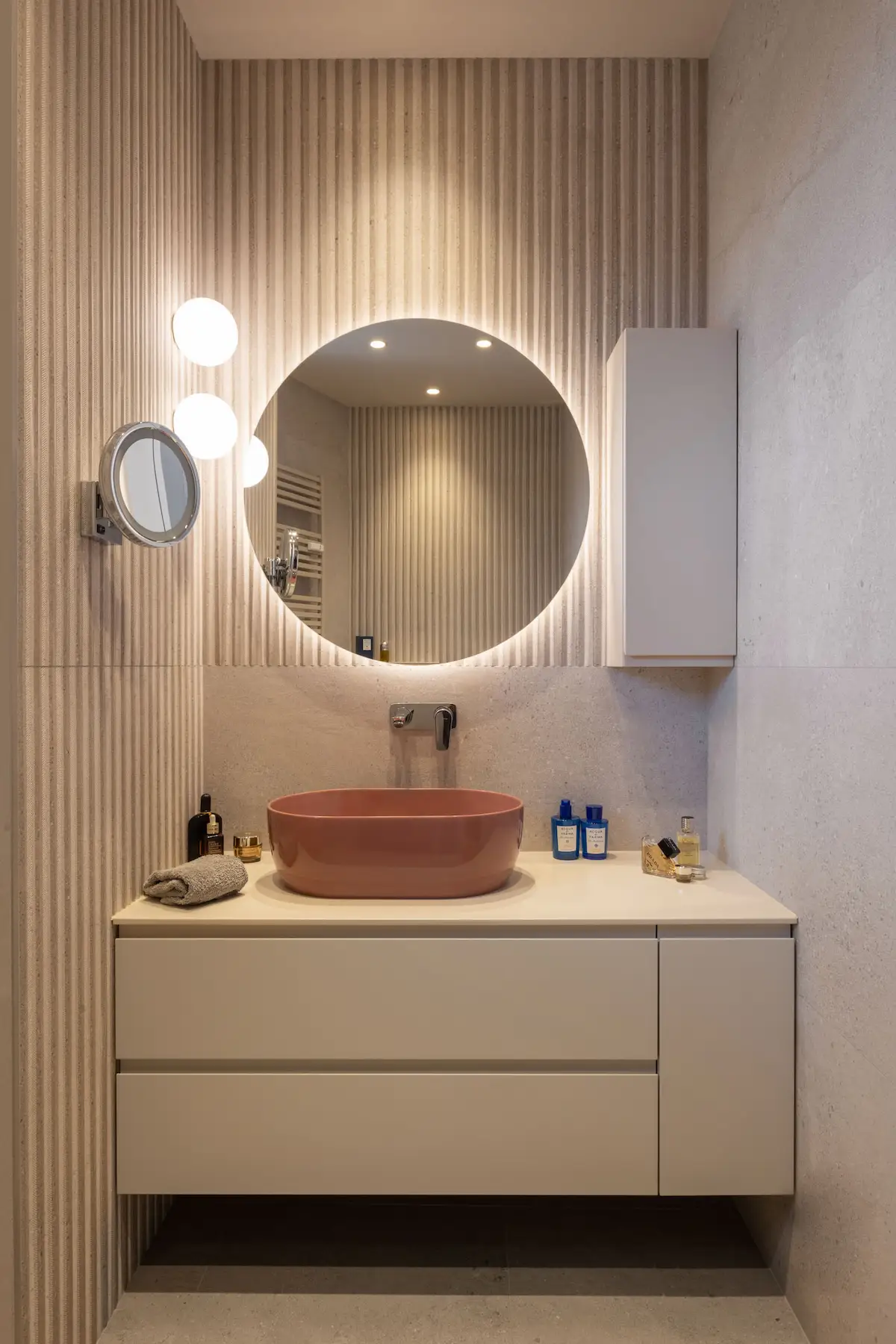 Mobile lavabo sospeso con specchio retroilluminato e lavabo rosa.