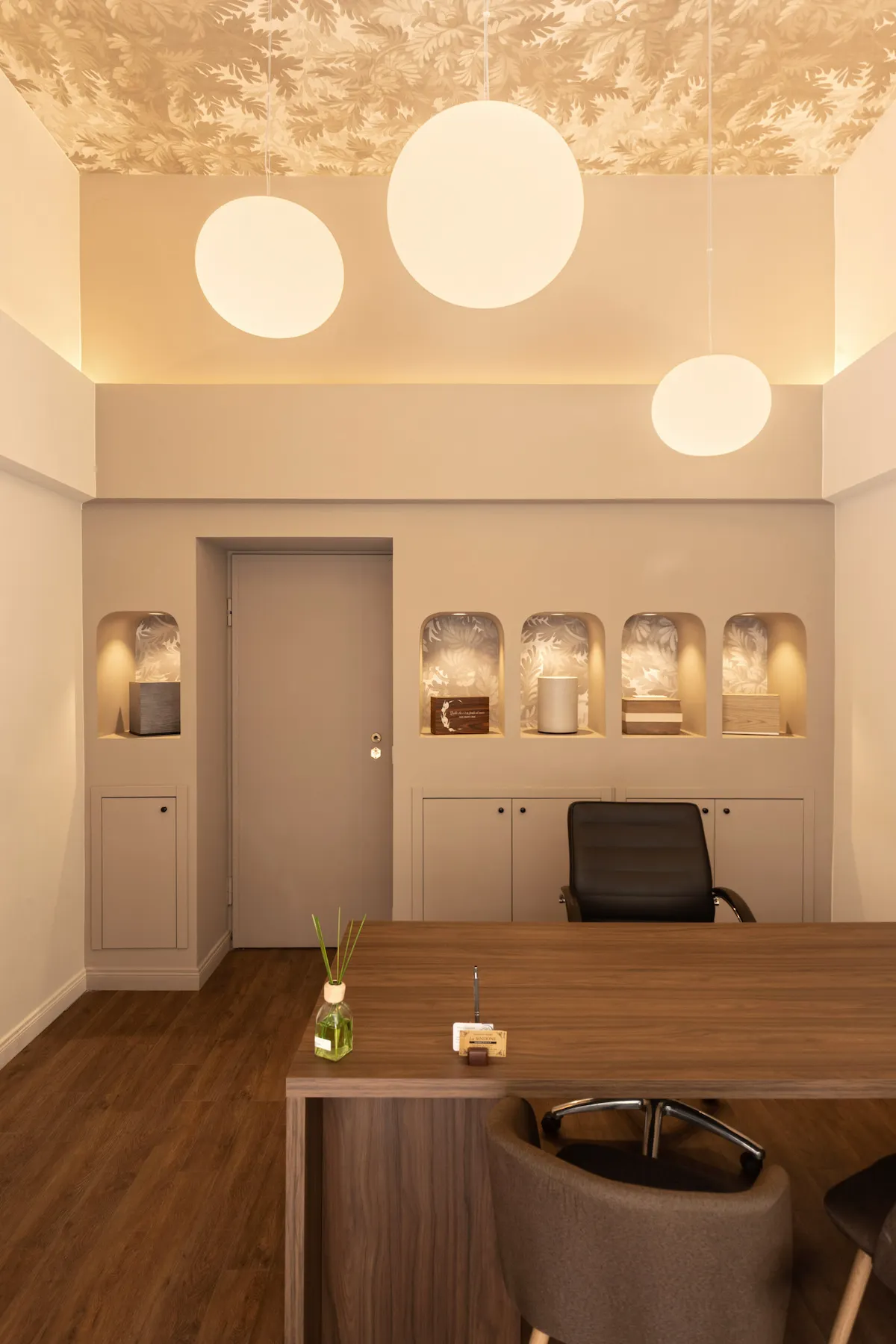 Progetto di interior design per un'agenzia funebre a Torino con illuminazione a sospensione, nicchie espositive e arredi su misura.