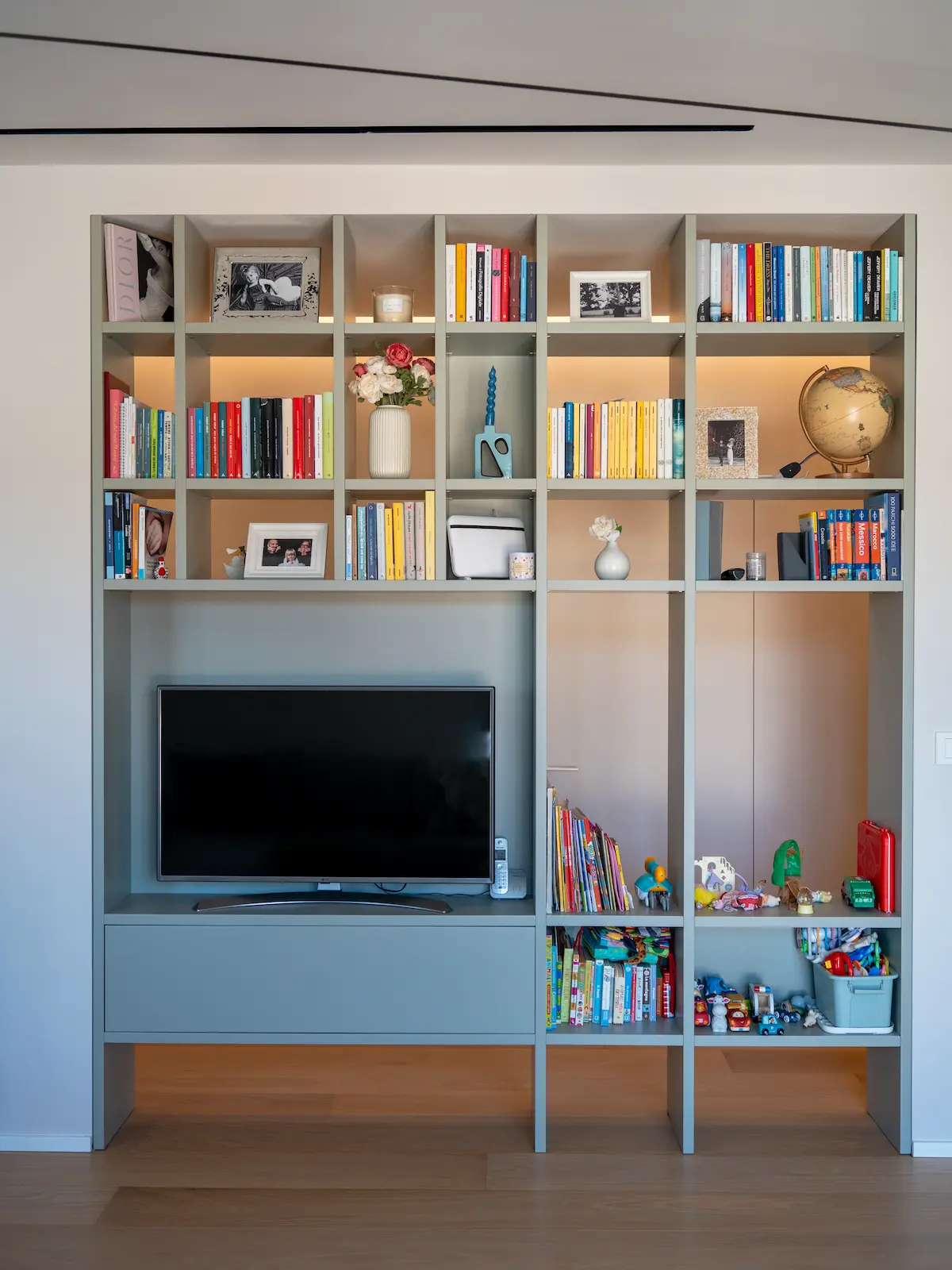 Libreria su misura con vano TV e illuminazione integrata nel progetto di interior design Blue in Green a Chieri